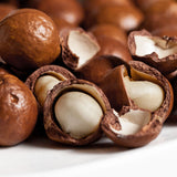 Macadamia nuts, including some shells open showing the nut.