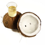 Coconut Cellular Extract light yellow in colour in a beaker sitting on a coconut cut in half