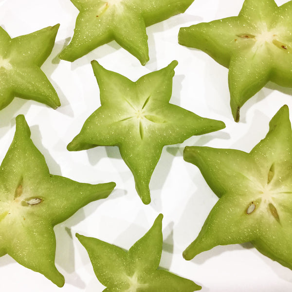 The Starfruit (Averrhoa carambola) is cut in half to show the bright green semi-ripe and star-shaped.