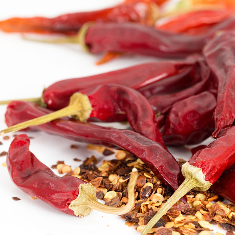 Whole dried bright red cayenne peppers with dried flakes, scientifically known as Capsicum annuum (frutescens)